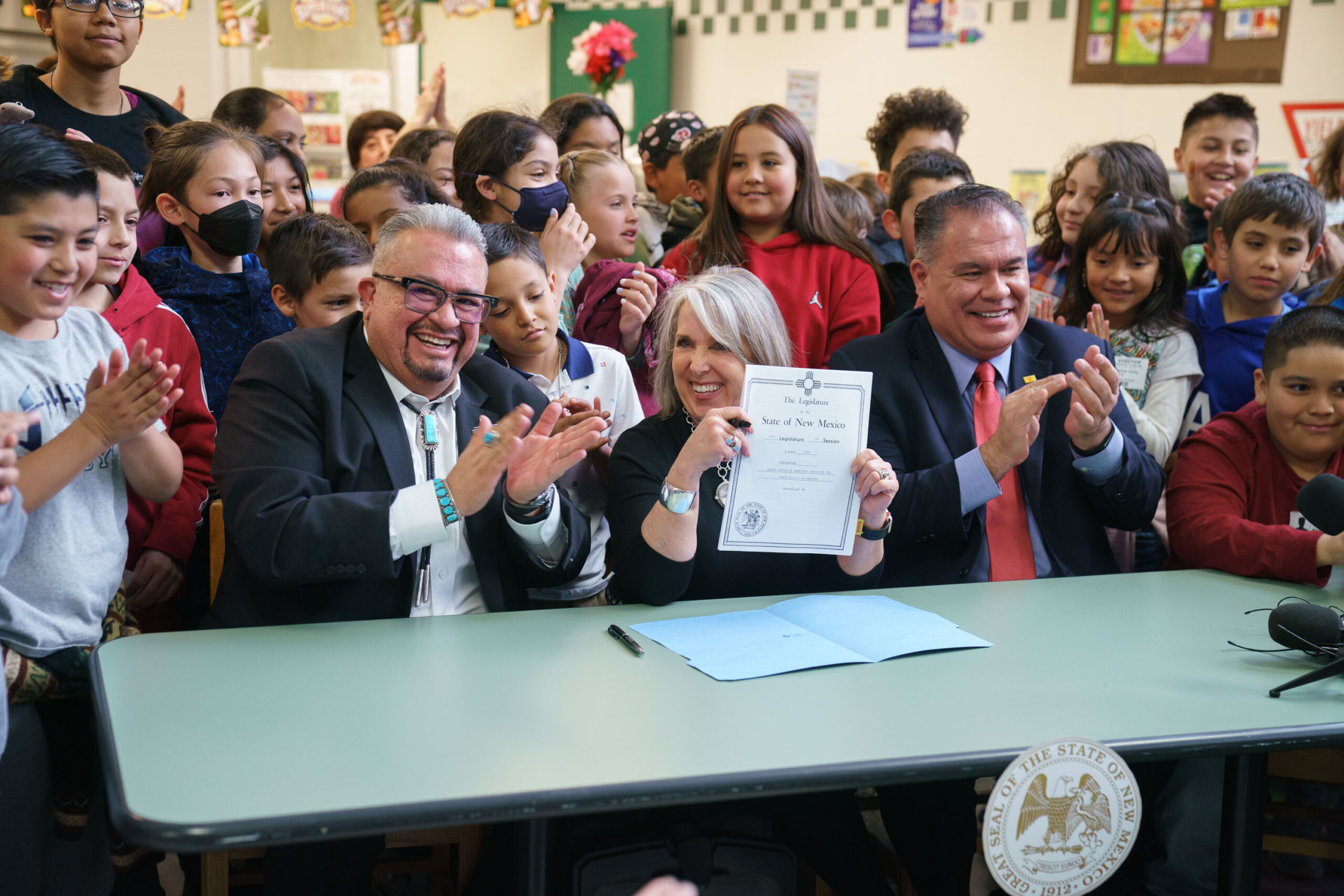 Governor Michelle Lujan Grisham signs Senate Bill 4 with sponsors Senator Michael Padilla and Senator Leo Jaramillo, at Pinon Elementary School in Santa Fe, new Mexico, March 27, 2023.
